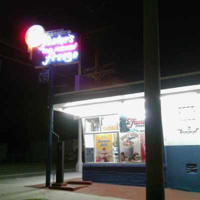 a neon sign and building for a Foster's Freeze				ice cream and hamburger stand at night.